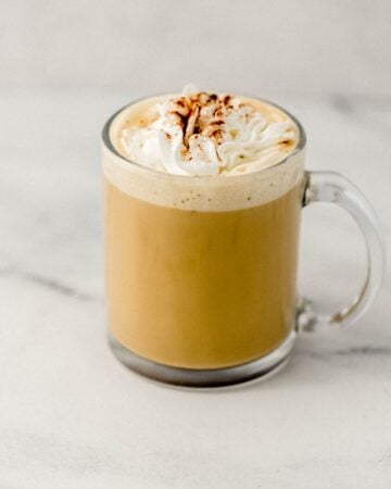 Close up side view of finished eggnog latte in glass mug.
