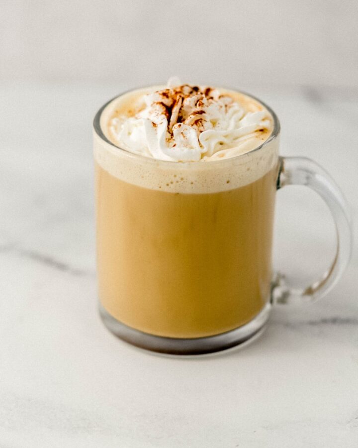 Close up side view of finished latte in glass mug.