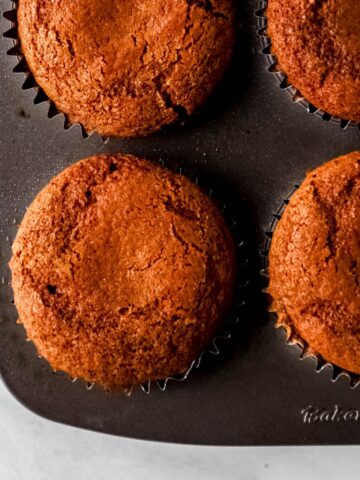 Overhead view of baked gingerbread muffins in muffin pan with liners.