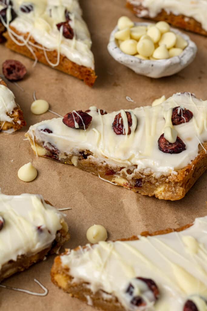 close up side view cranberry bliss bars on brown parchment paper
