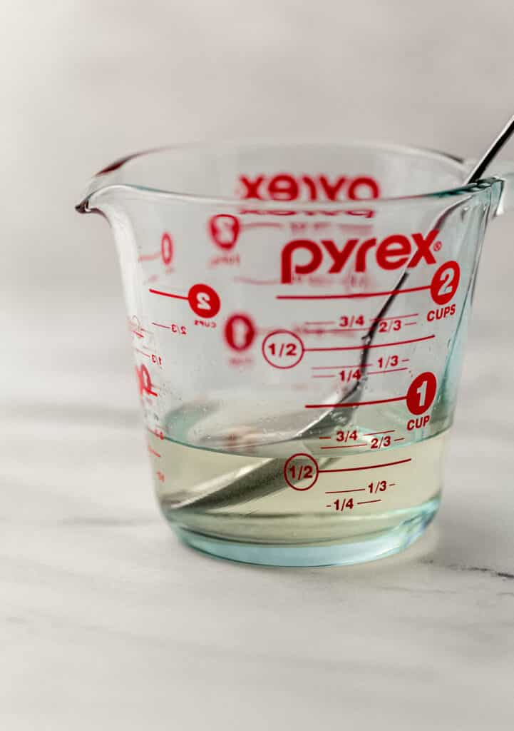 close up side view of Pyrex and spoon with vinegar, salt, and sugar combined