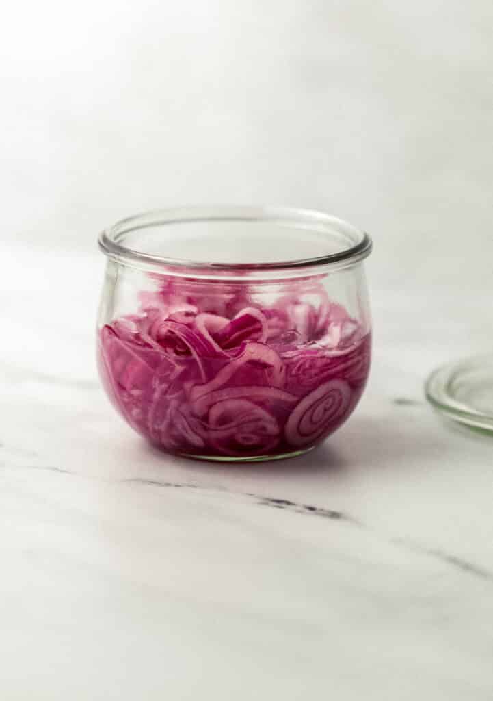 close up side view quick pickles onions in jar
