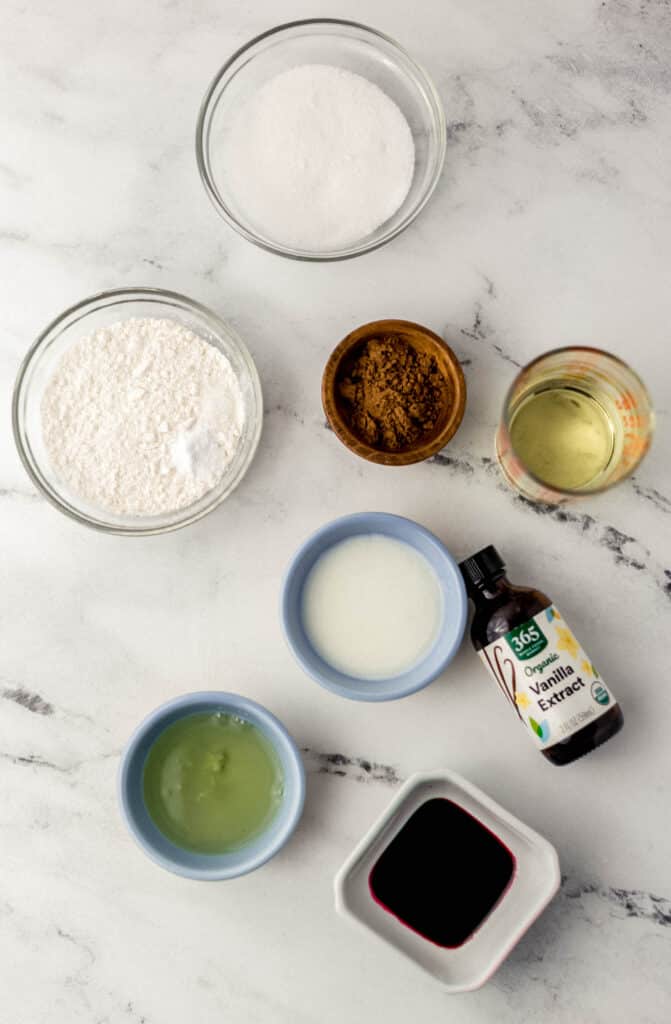 ingredients needed to make small batch red velvet cupcake in separate bowls on marble surface 