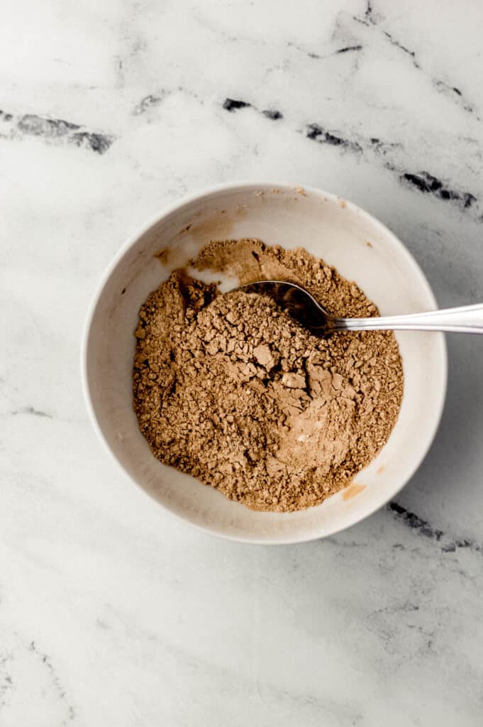 dry ingredients for red velvet cupcakes in small white bowl with spoon