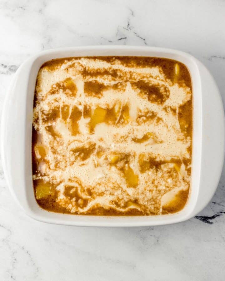 Flour mixture added to peach mixture in square white baking dish. 
