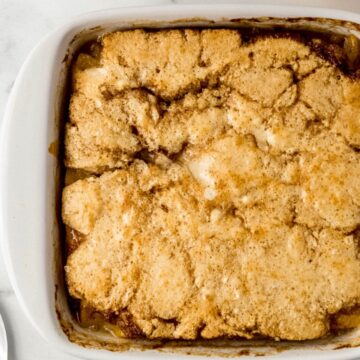 Close up overhead view of finished peach cobbler in square white baking dish.