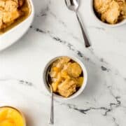 Overhead view of bowls of peach cobbler on marble surface.