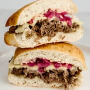 Close up view of finished sandwich halves stacked on top of white plate.