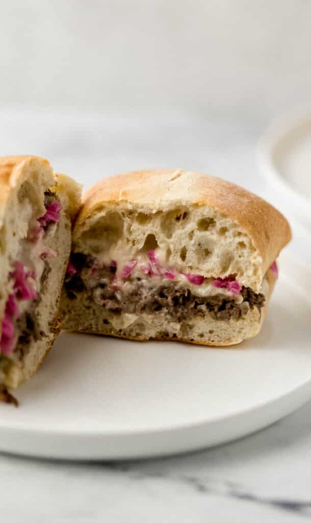 close up side view of sandwich cut in half on round white plate