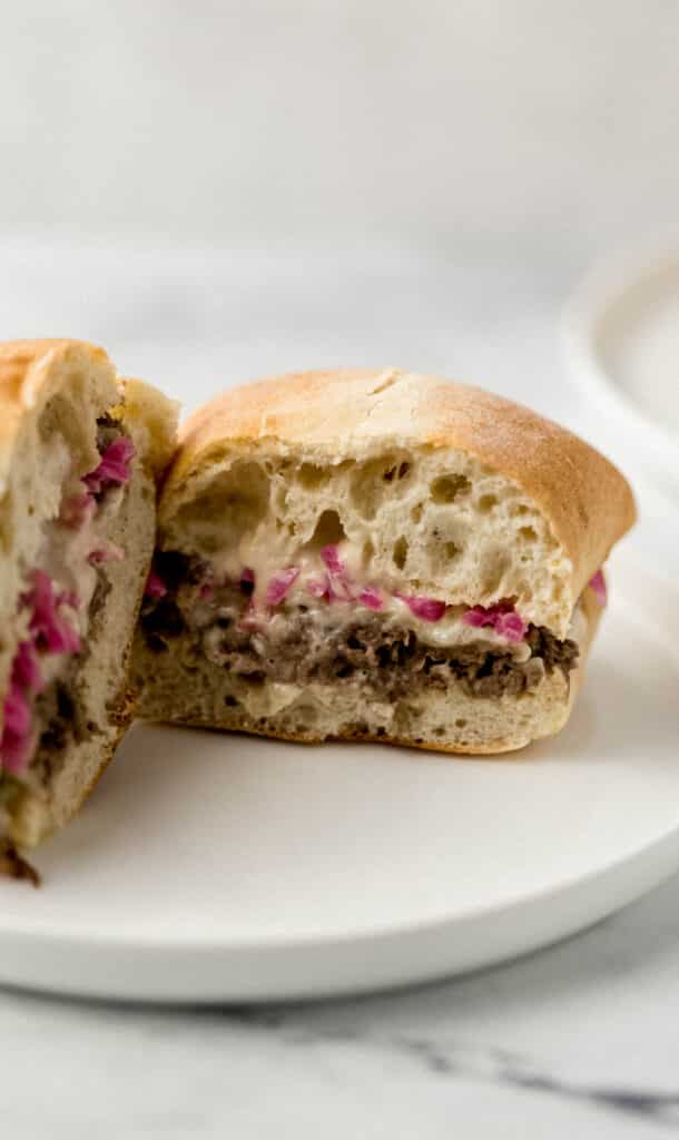 close up side view of sandwich cut in half on round white plate 