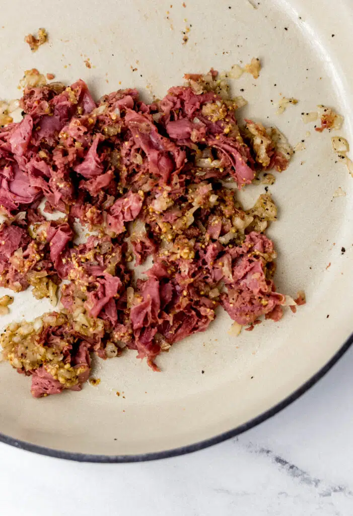 corned beef added to the onion mixture in the pan