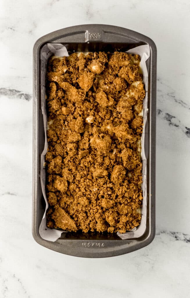peach bread mixture topped with brown sugar and butter in loaf pan