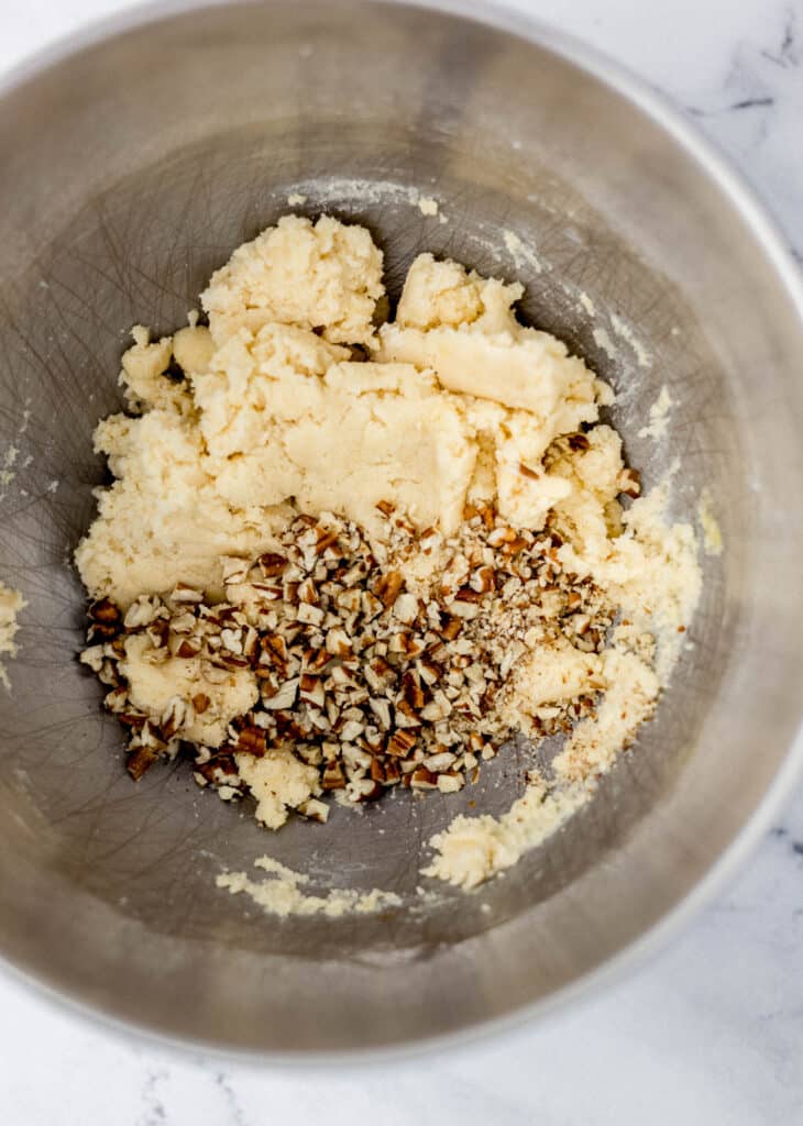 cookie dough in mixing bowl with chopped pecans 