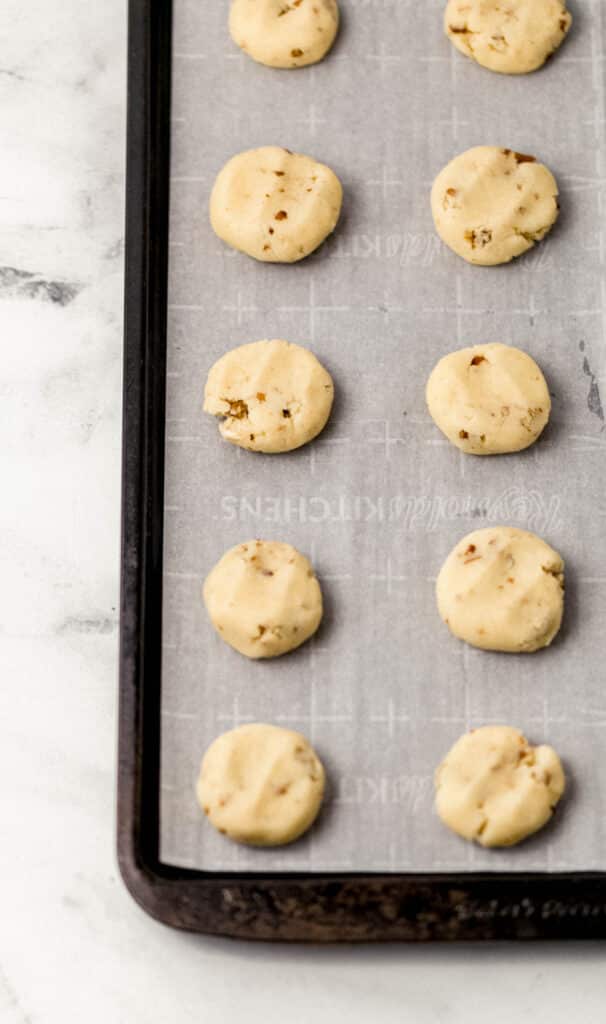 flattened cookie dough on parchment lined baking sheet 