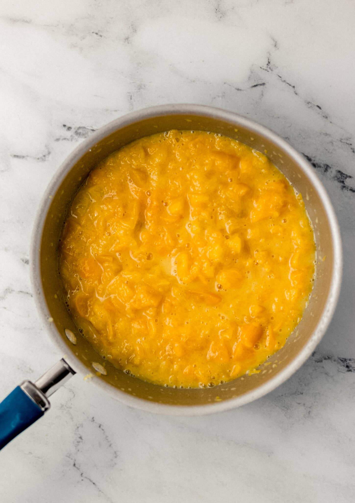 ingredients to make peach jam combined together in saucepan