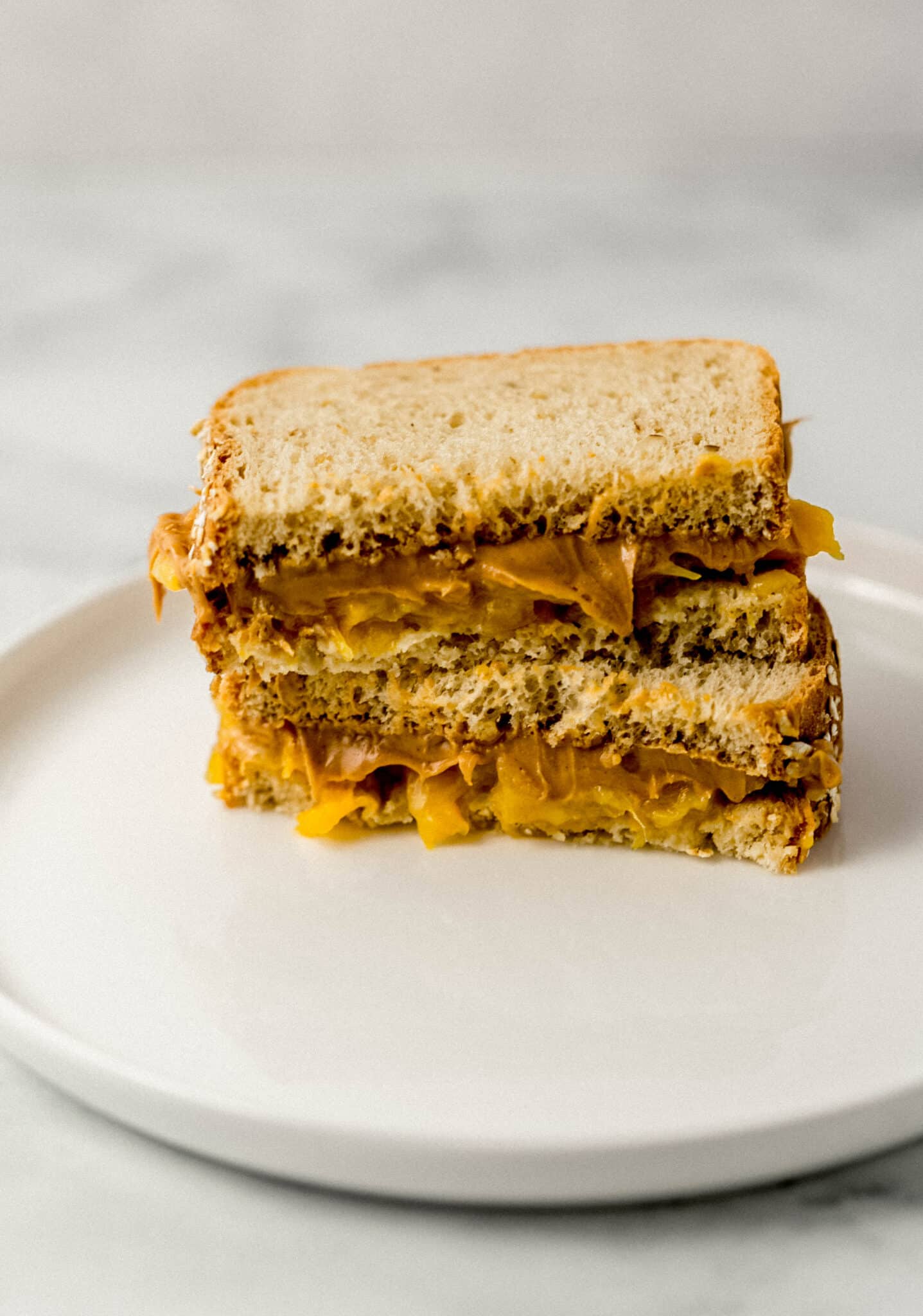 close up side view sandwich cut in half on white plate