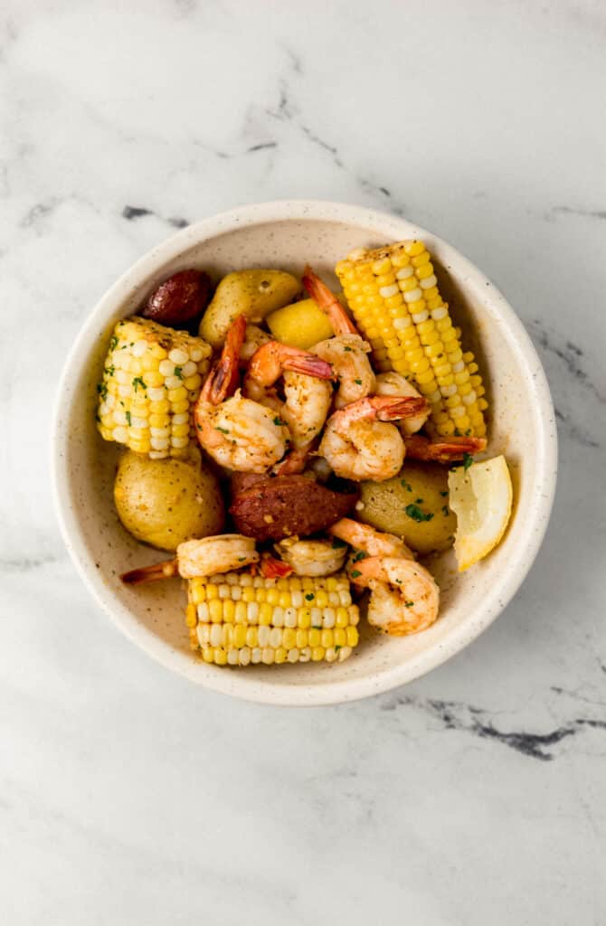 single serving of cooked shrimp boil in large white bowl 