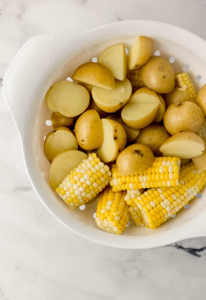 parboiled potatoes and corn in large white strainer