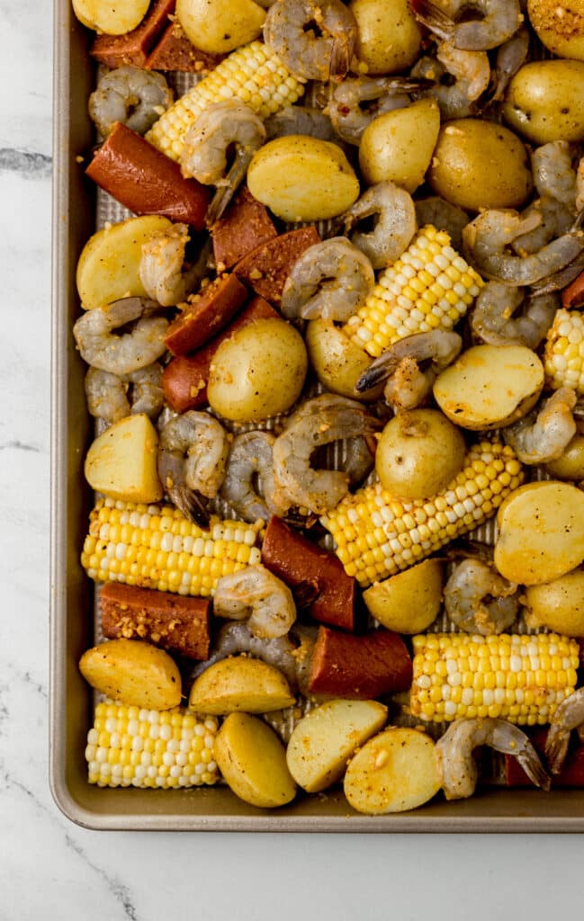 unbaked ingredients for shrimp boil on sheet pan before placing in the oven 