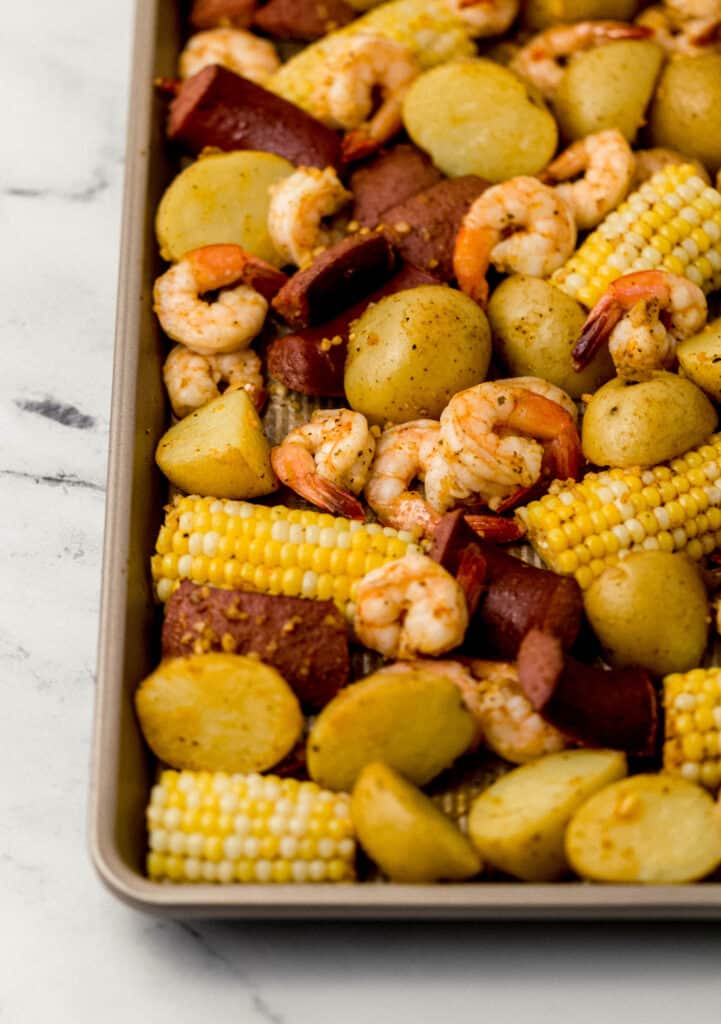 close up side view of cooked shrimp boil ingredients on sheet pan 