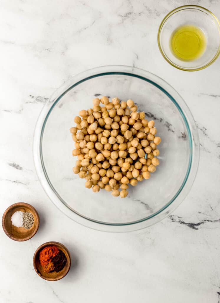 ingredients needed to make spicy chickpea recipe in separate bowls on marble surface