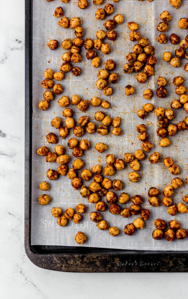 parchment-lined baking sheet with seasoned chickpeas on it.