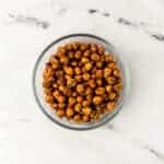 overhead view of chickpeas in a glass bowl on marble surface