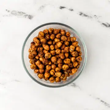 overhead view of chickpeas in a glass bowl on marble surface