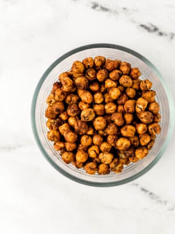 overhead view spicy chickpeas in a glass bowl on marble surface