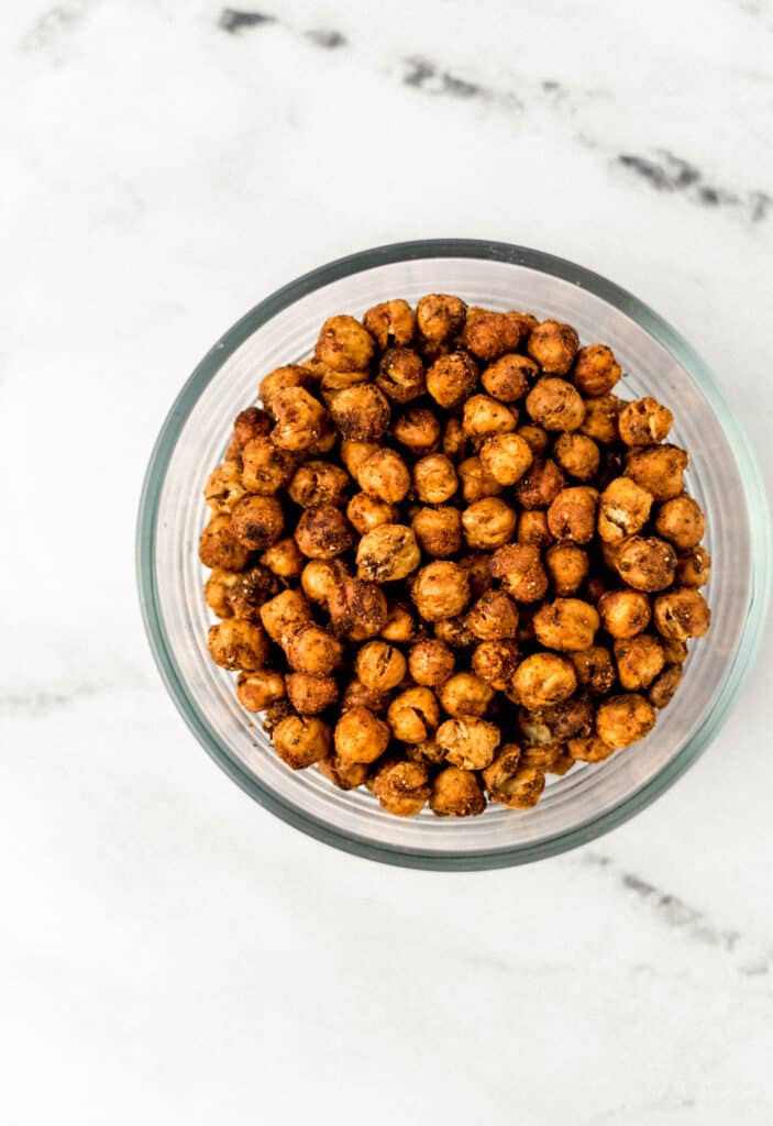 overhead view spicy chickpeas in a glass bowl on marble surface