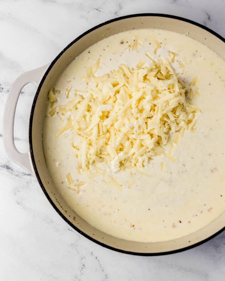Shredded white cheddar added to braiser pan with the other mac and cheese sauce ingredients. 