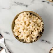 Overhead view of single serving of mac and cheese in bowl by forks.