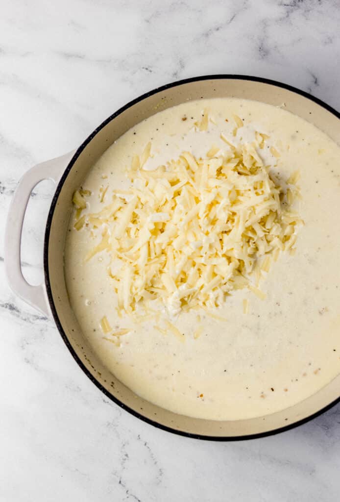 shredded white cheddar added to pan for cheese sauce 