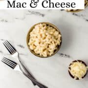 Overhead view of mac and cheese in a bowl by forks on pin with text overlay.