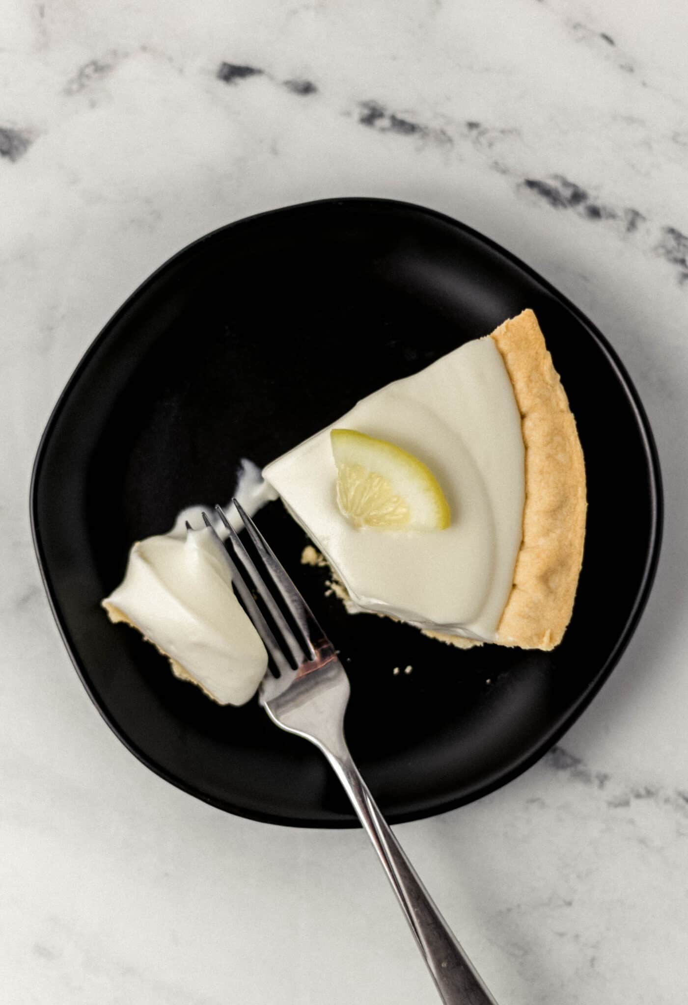 slice of pie on small black plate with fork in it