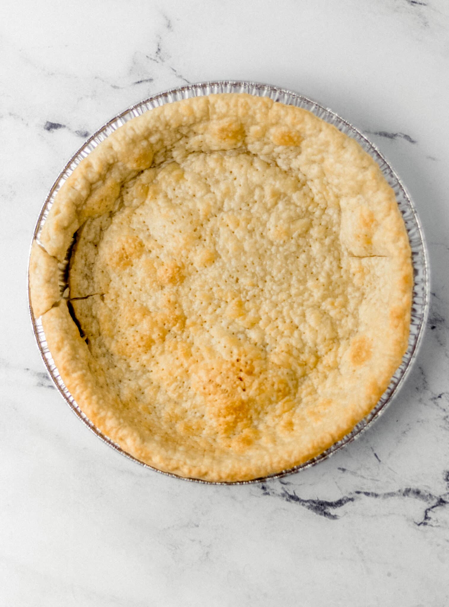 overhead view of baked pie crust on marble surface