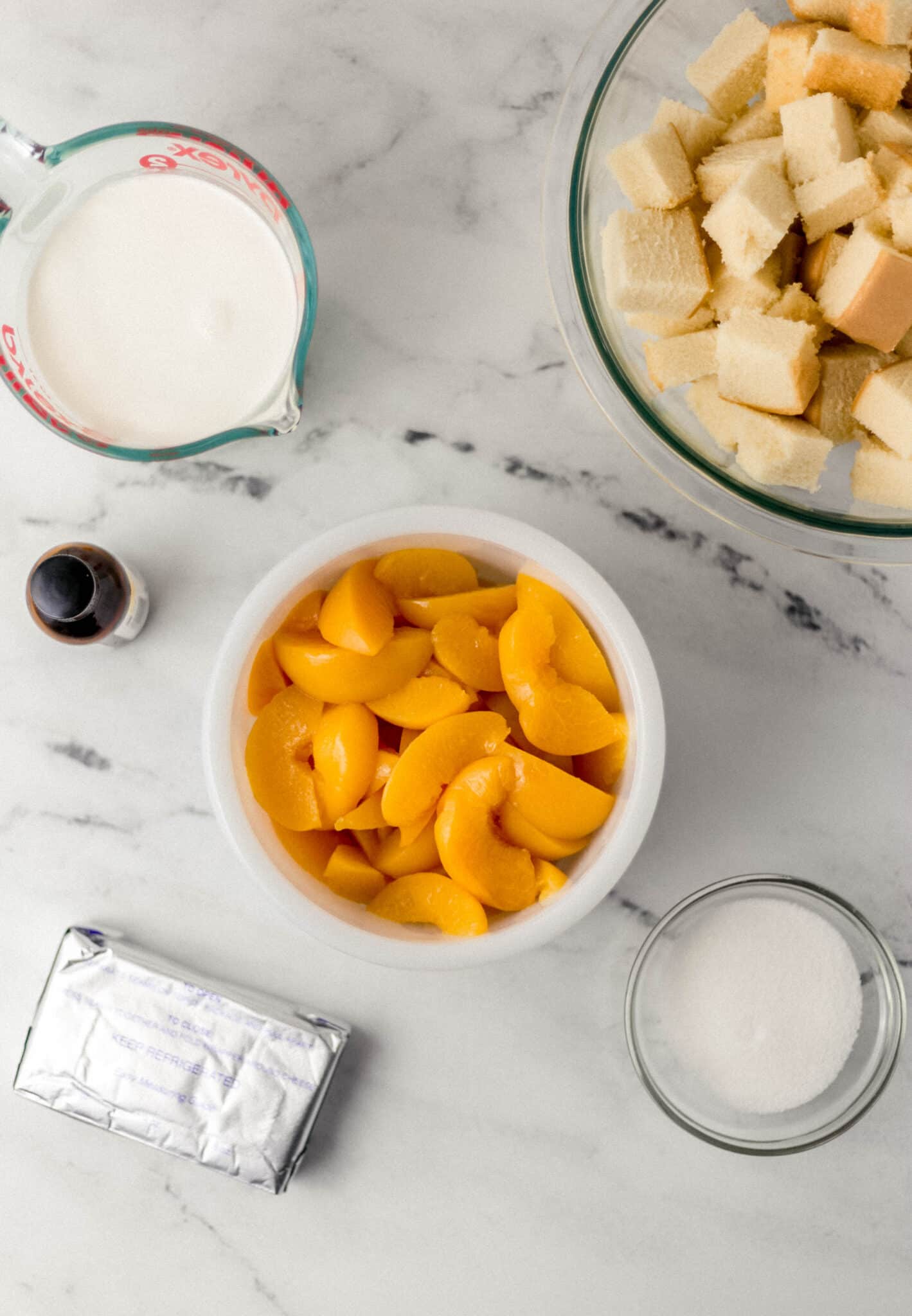overhead view of ingredients needed for peach trifle in separate containers on marble surface