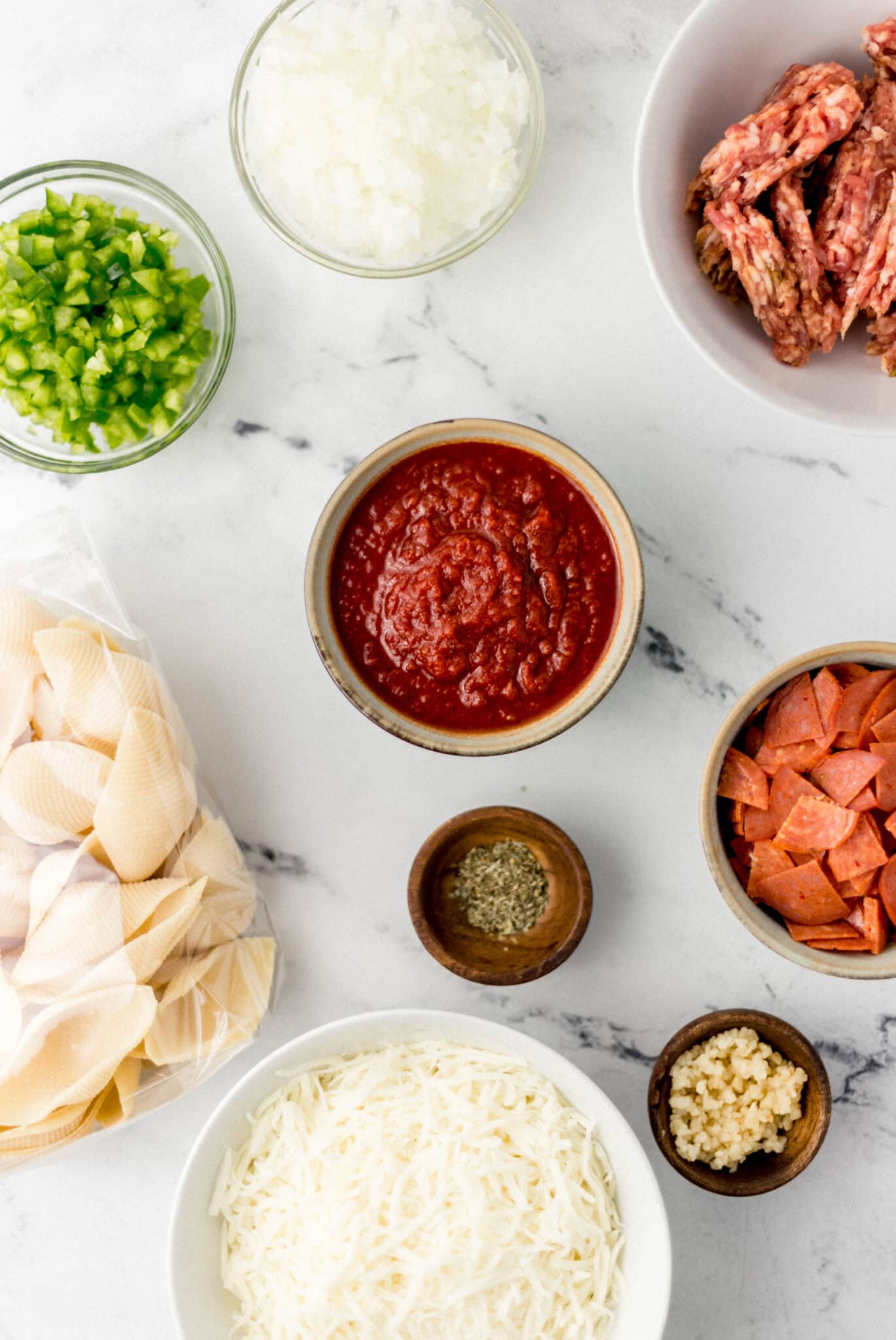 overhead view of stuffed shells in separate bowls on marble surface 