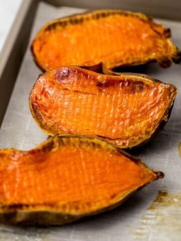 Close up view of finished sweet potatoes on parchment lined sheet pan.