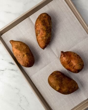 Four potatoes on parchment lined sheet pan.