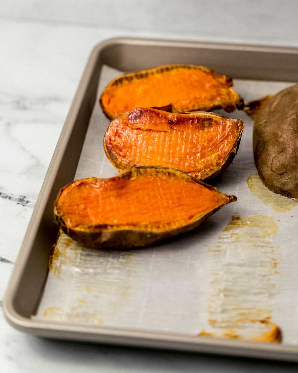 Close up front view of finished sweet potatoes on parchment lined sheet pan.
