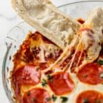 Close up view of finished pepperoni dip with pieces of toasted bread dipped in it.