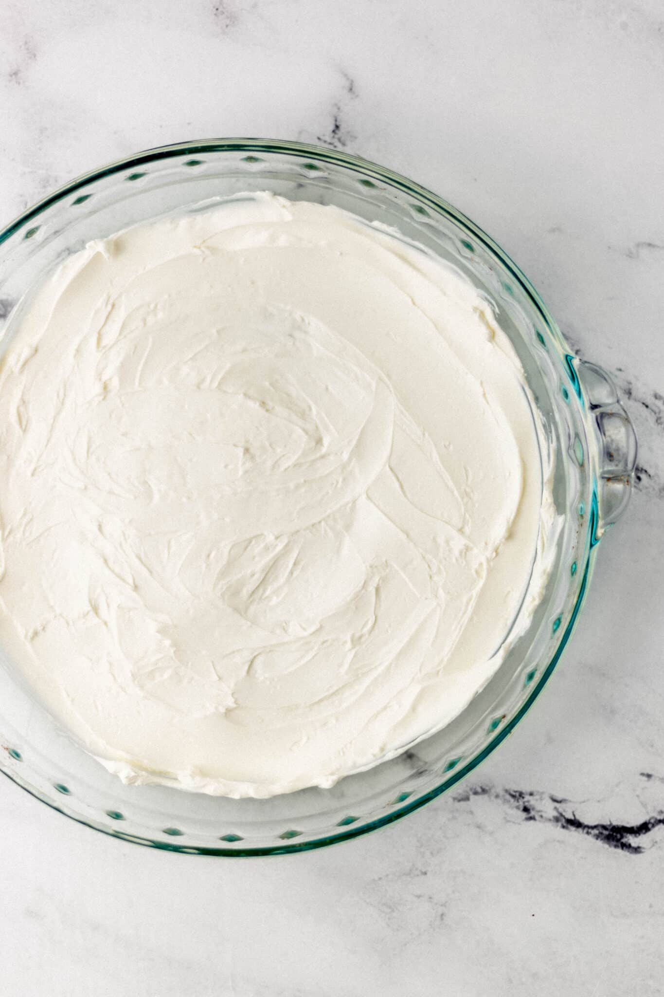 cream cheese spread in the bottom of a glass baking dish 