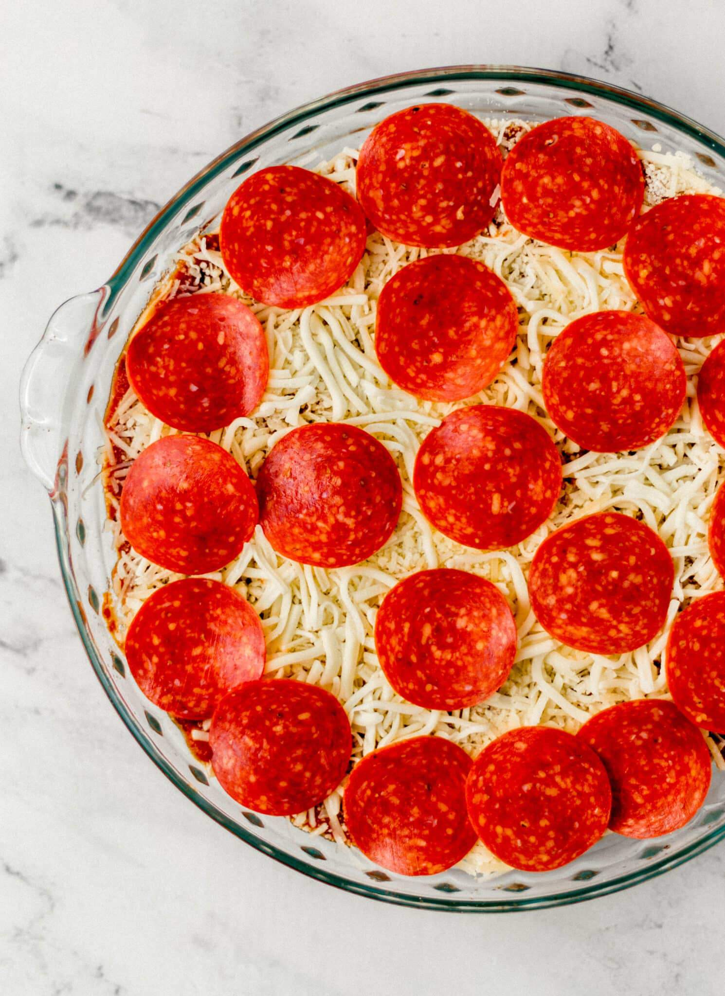 unbaked pizza dip in glass baking dish 