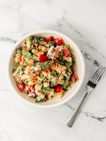 ranch blt pasta salad in white bowl beside a fork