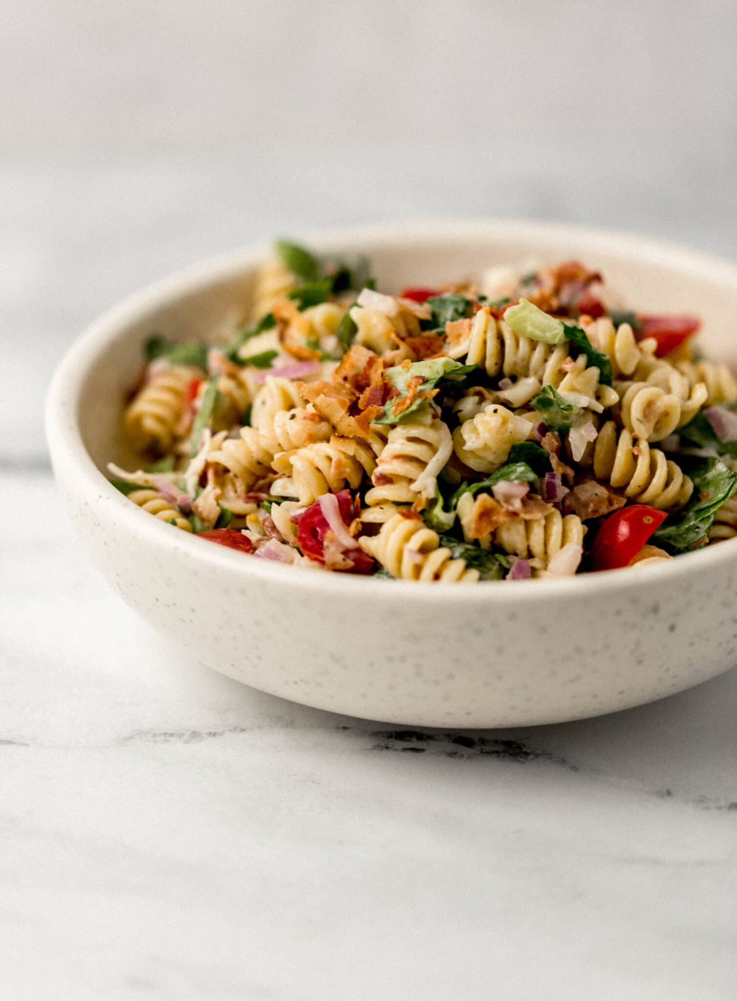 close up side view pasta salad in white bowl