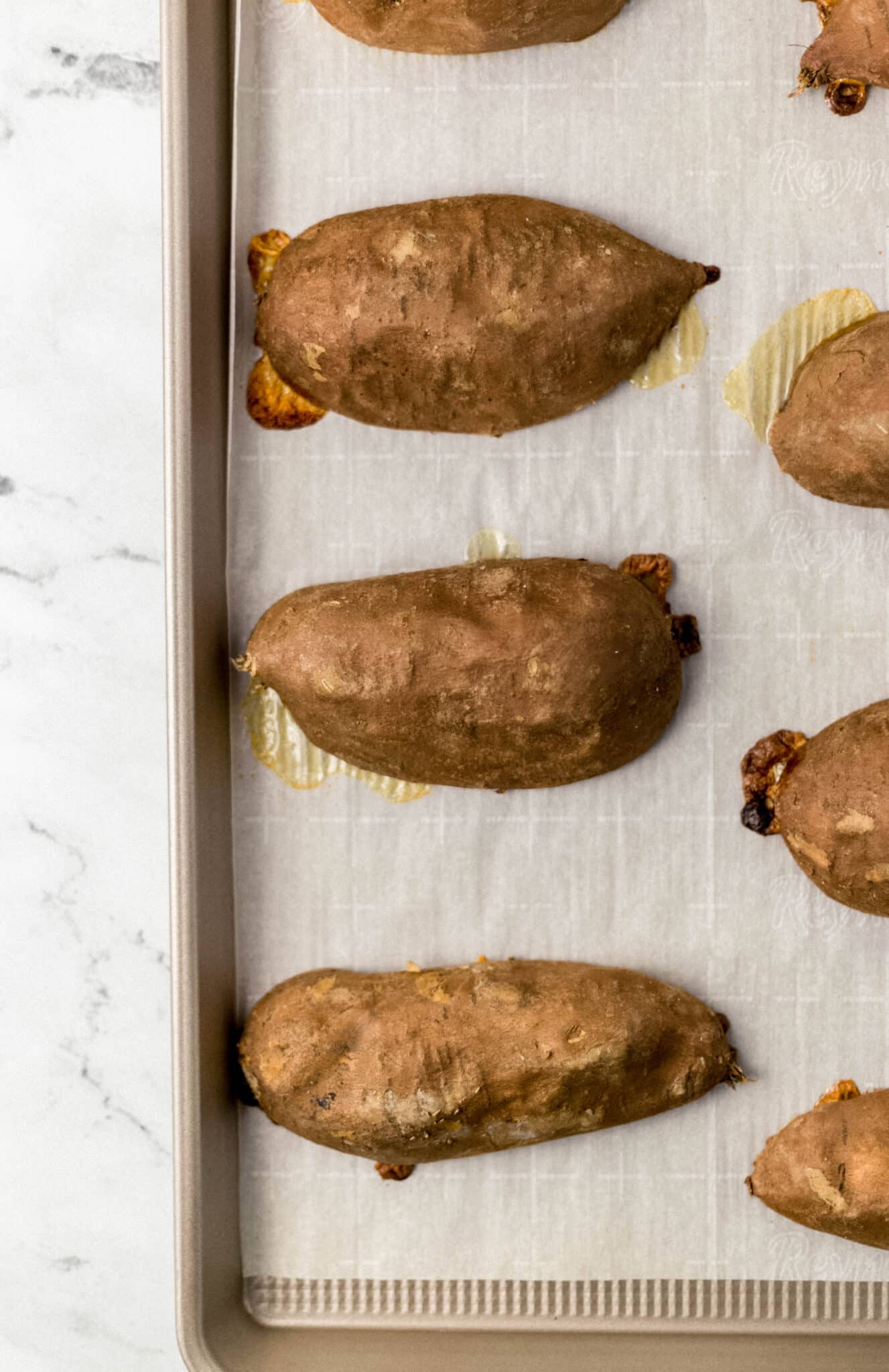 cooked sweet potato halved on parchment-lined sheet pan 