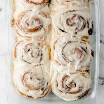 overhead view of finished rolls in glass baking dish topped with cream cheese frosting