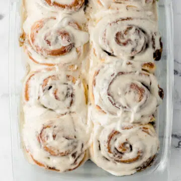 overhead view of finished rolls in glass baking dish topped with cream cheese frosting
