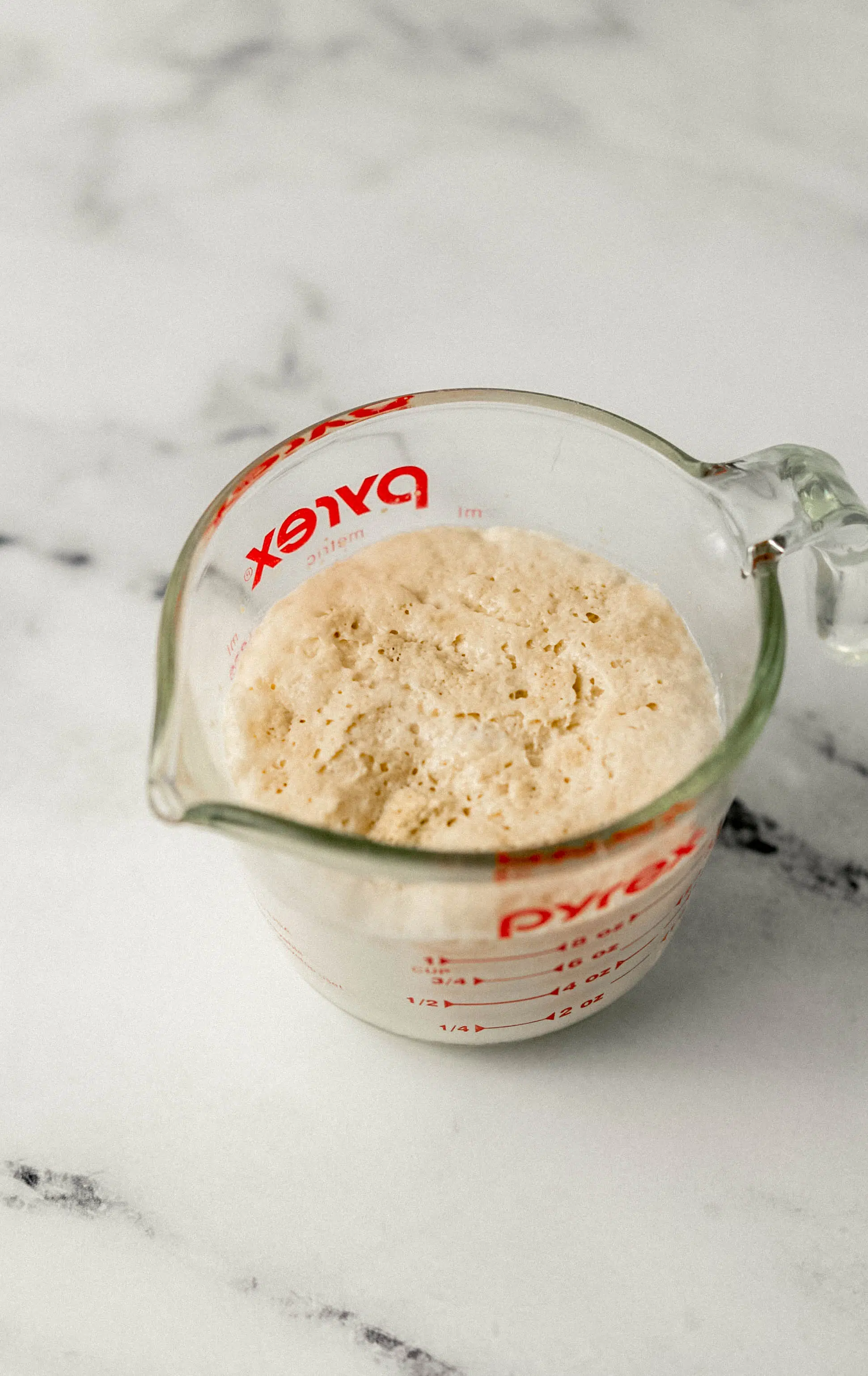 warm milk and yeast in glass measuring cup